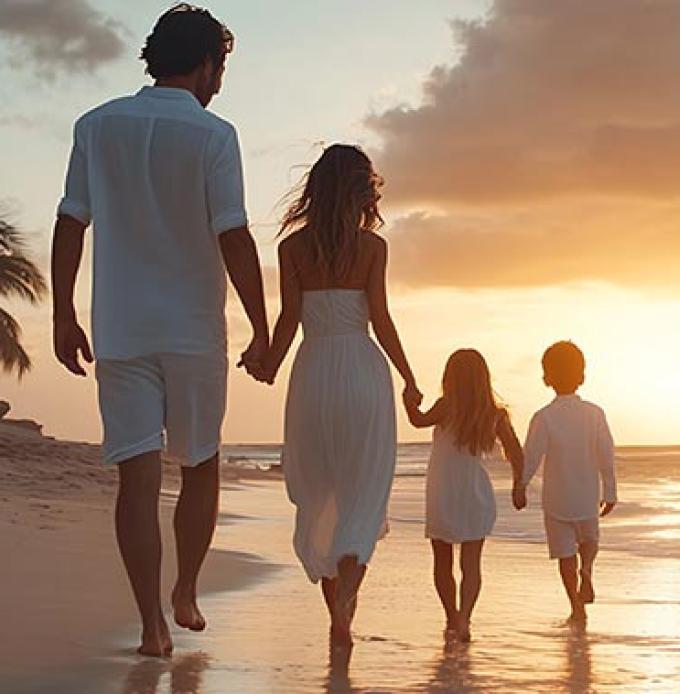Eine junge Familie mit Eltern und zwei kleinen Kindern am traumhaften Strand im Urlaub (Foto: © The Little Hut - Adobe Stock)